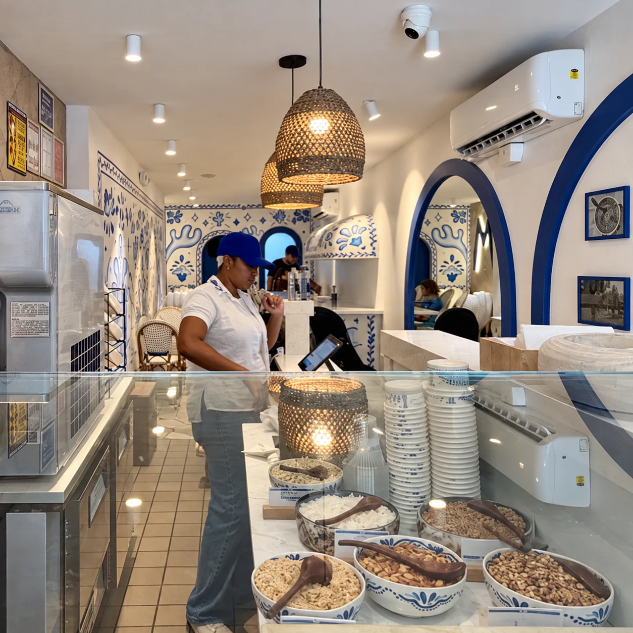 AI-retouched photograph of the Mythos service counter, woven pendant lights and blue wall arches